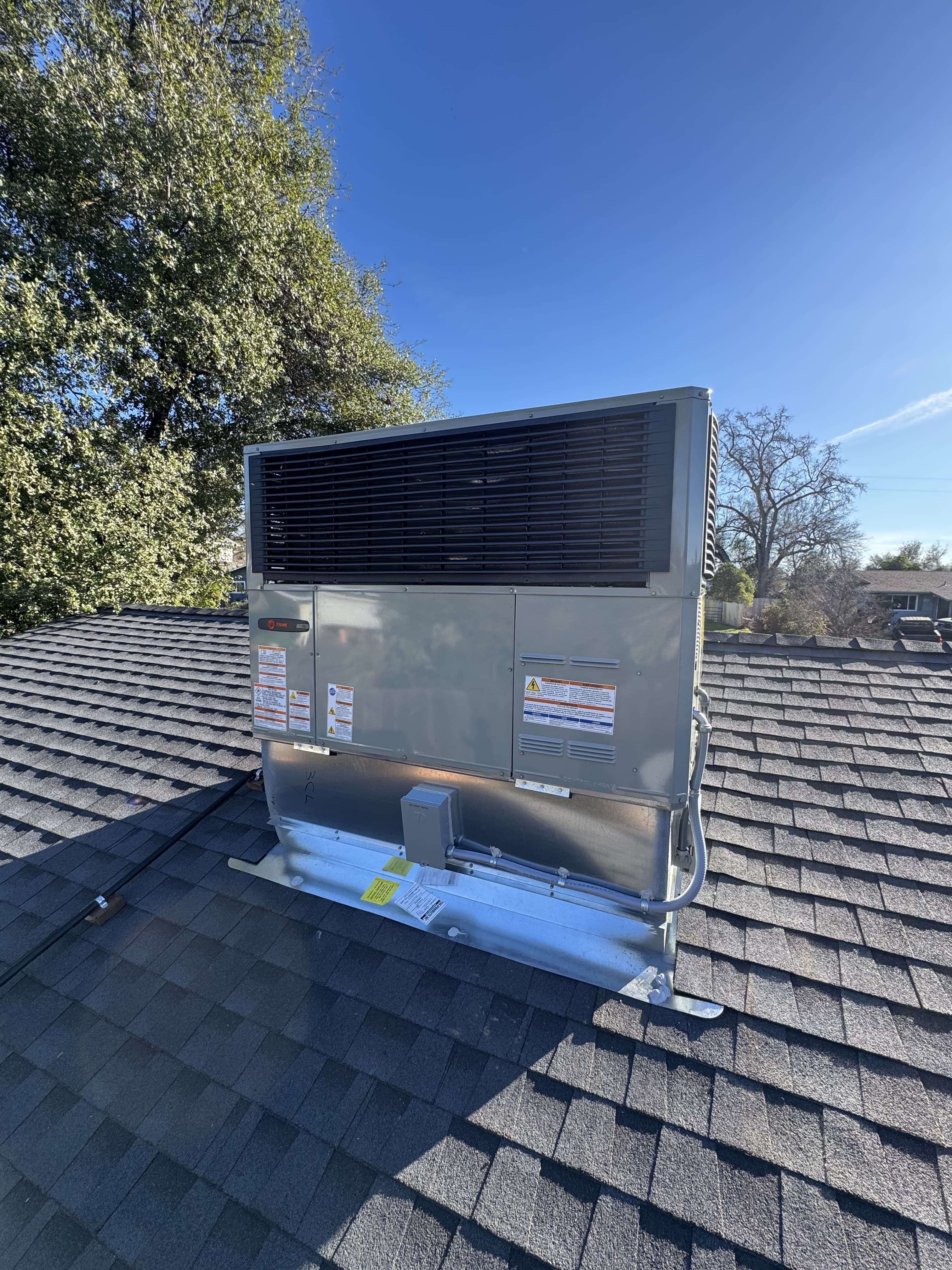 Trane rooftop package unit installation against a clear blue sky